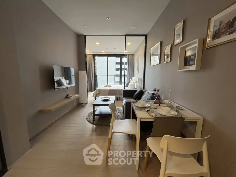 Modern open-plan living room with dining area and bedroom, featuring stylish decor and natural light.