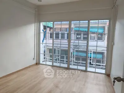 Spacious empty room with large windows and wooden flooring, ideal for customization.