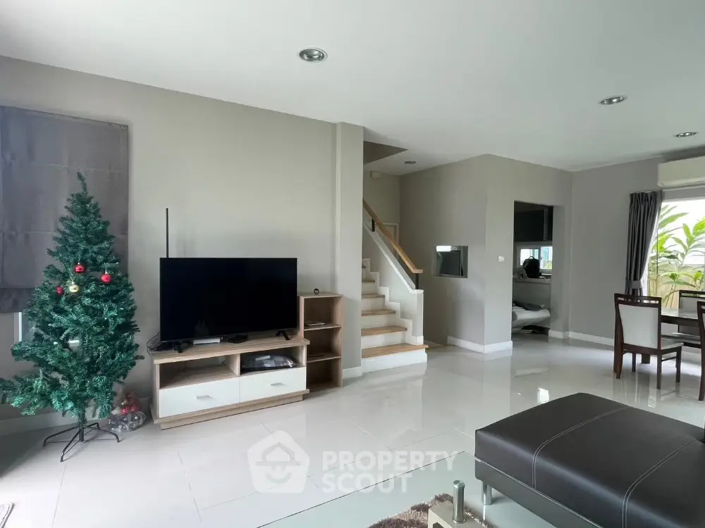 Modern living room with TV, Christmas tree, and dining area in open layout home.