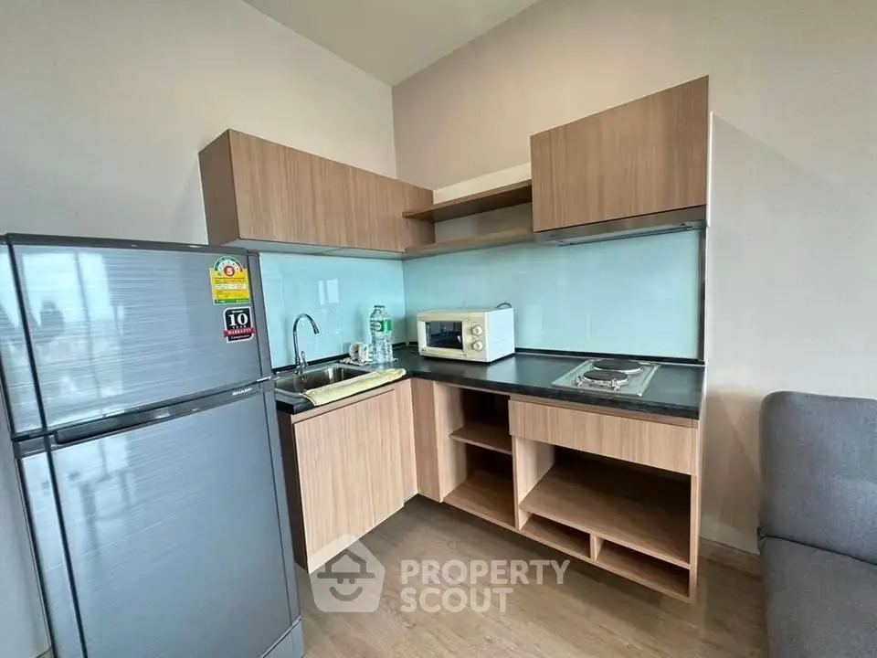 Modern compact kitchen with sleek appliances and wooden cabinetry in a cozy apartment setting.