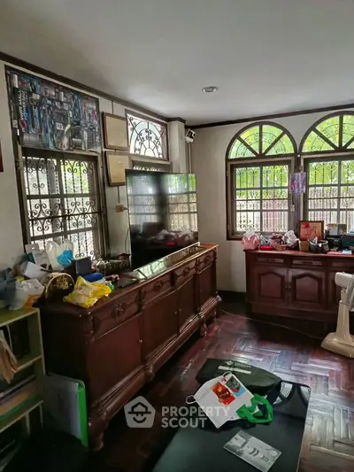 Cozy living room with wooden furniture and large windows offering natural light.