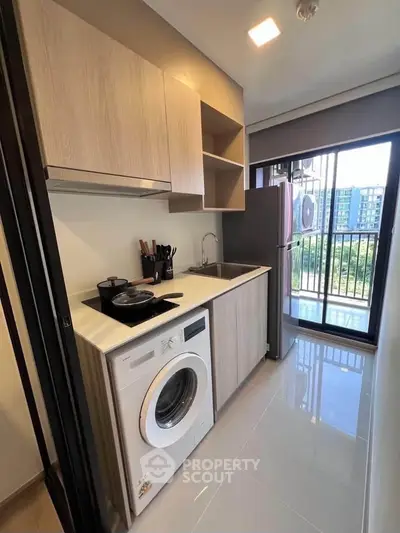 Modern kitchen with washing machine and balcony view in stylish apartment