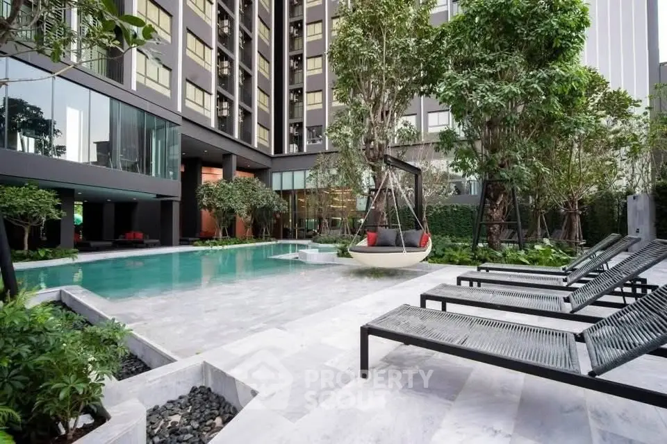 Luxurious modern apartment pool area with stylish lounge chairs and lush greenery.
