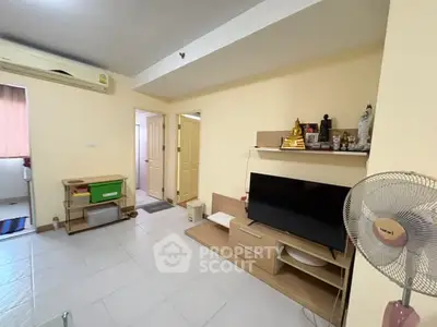 Cozy living room with modern TV setup and air conditioning in a well-lit apartment.