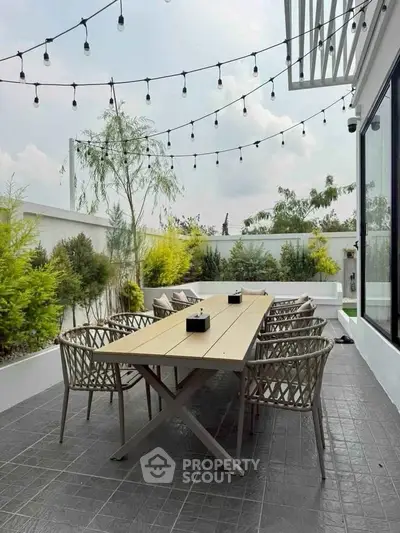 Chic outdoor patio with string lights and modern dining set, perfect for entertaining.
