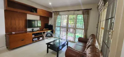 Spacious living room with leather sofa and large windows overlooking garden