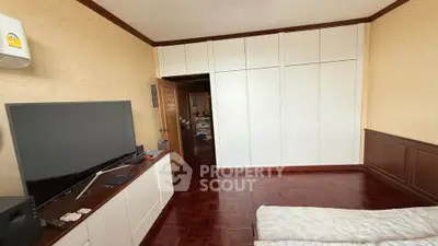 Spacious bedroom with large wardrobe and modern TV setup