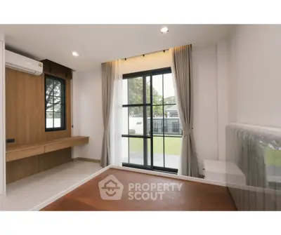 Modern bedroom with large window and garden view, featuring sleek wooden flooring and minimalist design.