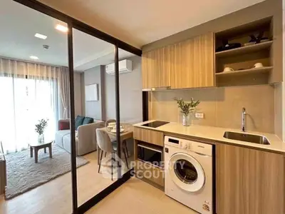 Modern open-layout kitchen with washing machine and cozy living area in stylish apartment.