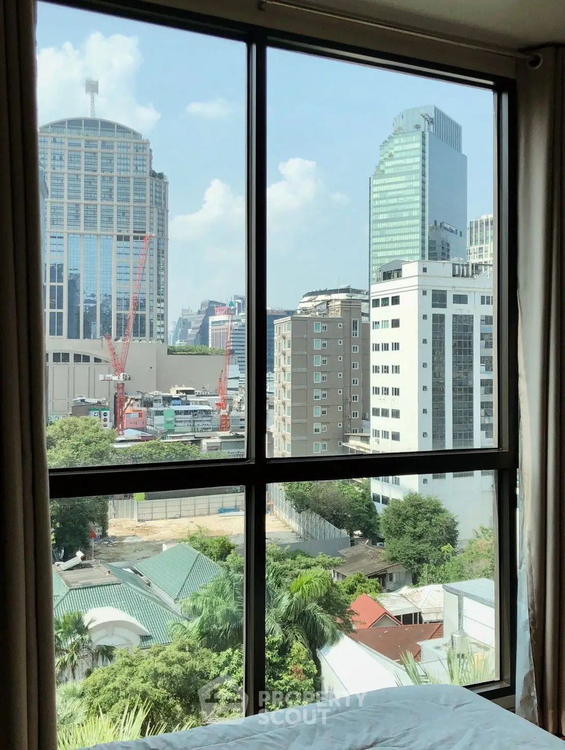 Stunning cityscape view from a modern window, showcasing urban architecture and greenery.