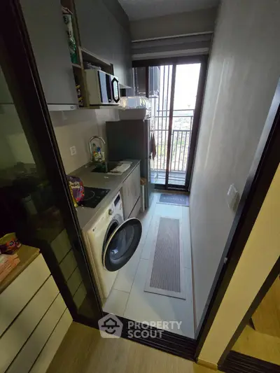 Compact kitchen with washing machine and balcony access in modern apartment