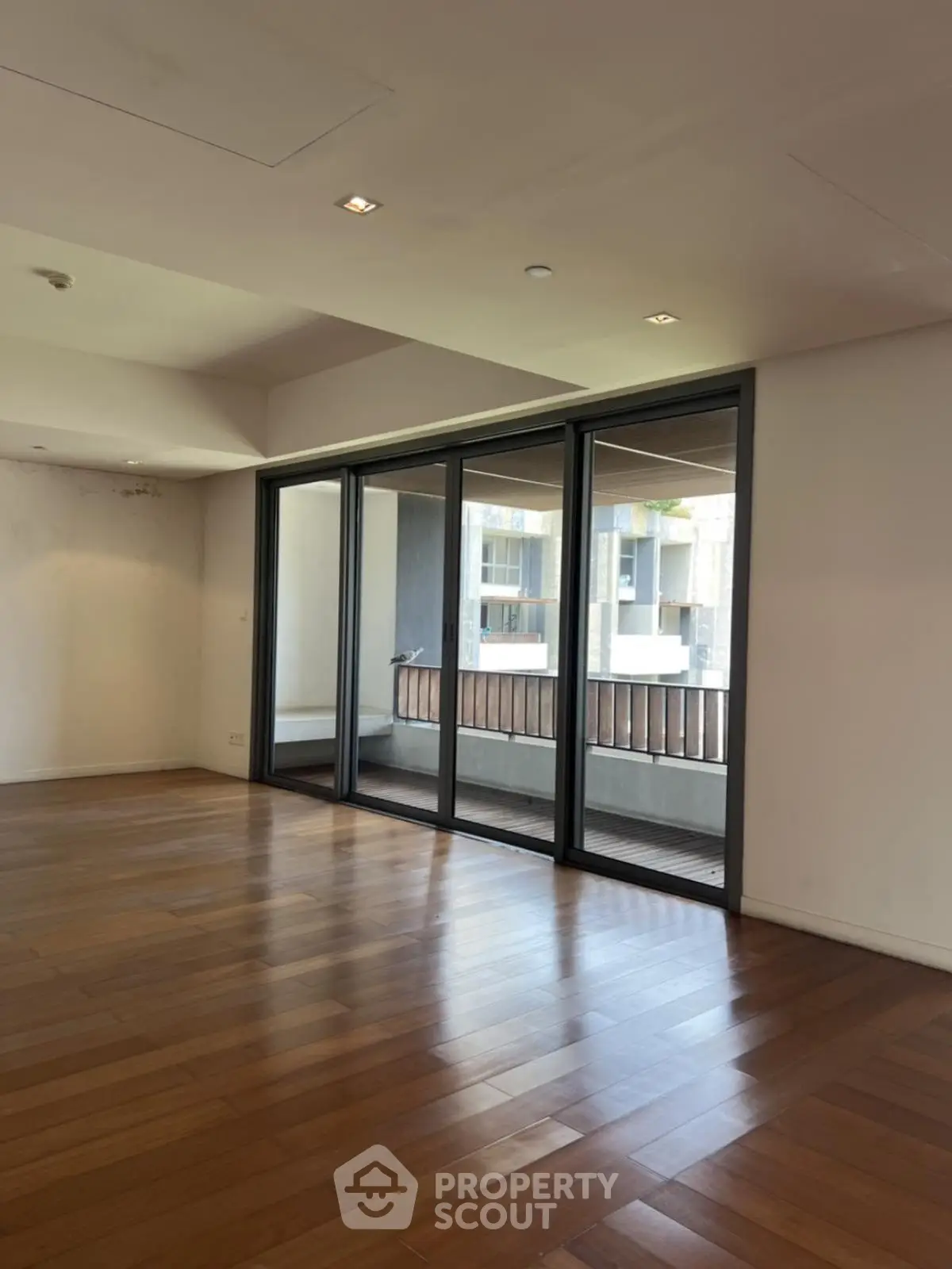 Spacious living room with wooden flooring and large sliding glass doors to balcony.