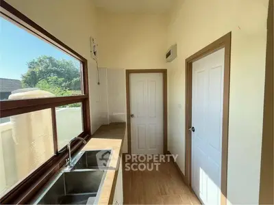 Bright kitchen with large window and wooden countertops, offering a serene view of greenery.