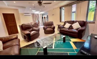 Spacious living room with leather sofas and modern glass coffee table in a cozy home setting.