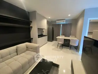 Modern living room with sleek furniture and open kitchen layout in a stylish apartment.