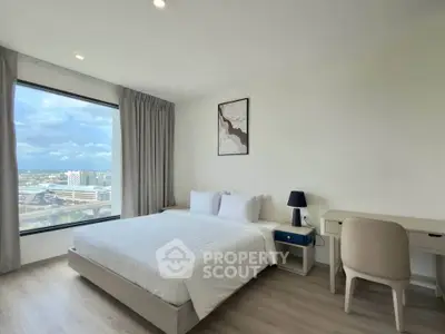 Modern bedroom with large window offering stunning city view, featuring a cozy bed and stylish desk.