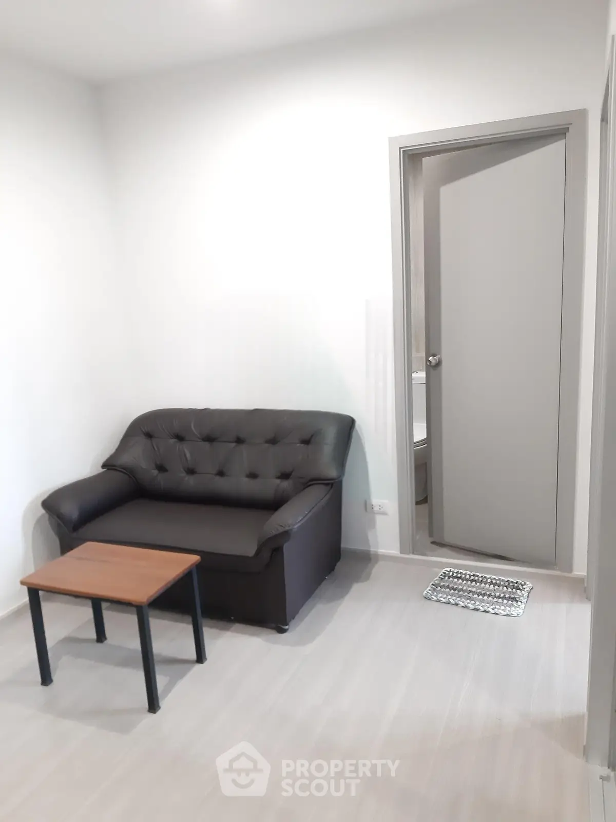 Cozy living room with black sofa and small wooden table, perfect for compact spaces.