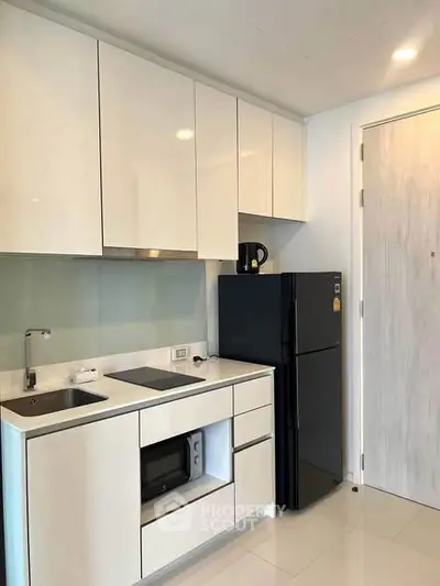 Modern kitchen with sleek cabinetry and black appliances in a contemporary apartment.
