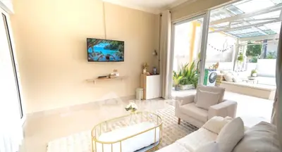 Bright and airy living room with modern decor and large windows opening to a lush patio.