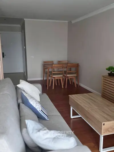 Modern living room with cozy sofa, wooden dining set, and stylish decor in a contemporary apartment.