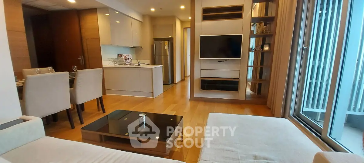 Modern open-plan living room with sleek kitchen and large windows for natural light.
