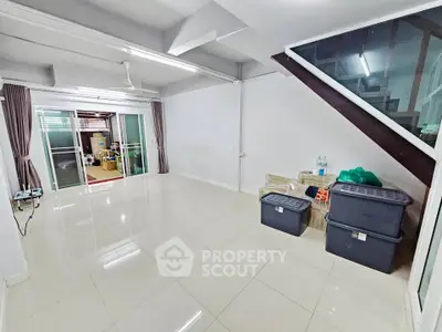 Spacious living room with modern tile flooring and staircase, ideal for customization.