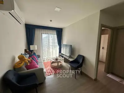 Modern living room with stylish decor and natural light, featuring a cozy sofa and flat-screen TV.