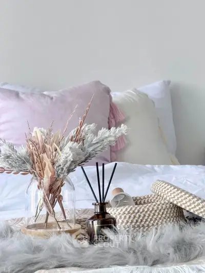 Cozy bedroom decor with soft pillows and elegant dried floral arrangement.