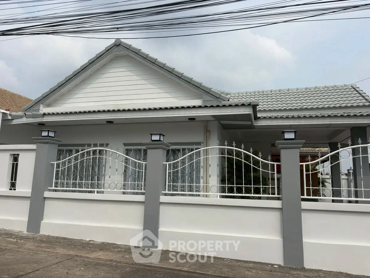 Charming single-story home with modern white facade and decorative fence.