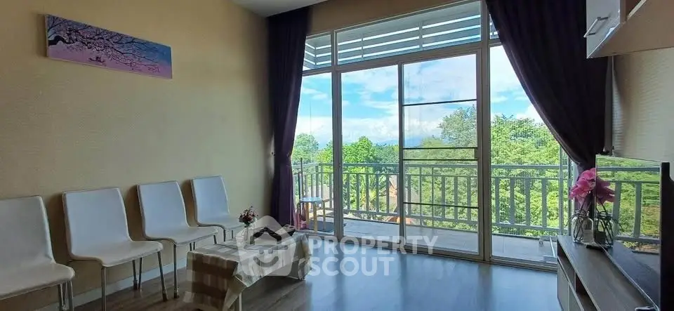 Bright living room with large windows and balcony offering stunning green views.