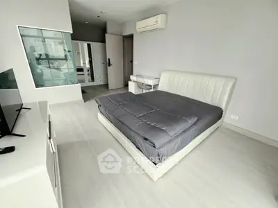 Spacious modern bedroom with sleek design and ample natural light, featuring a comfortable bed and stylish decor.