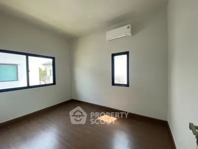 Spacious empty room with wooden flooring and air conditioning, perfect for customization.