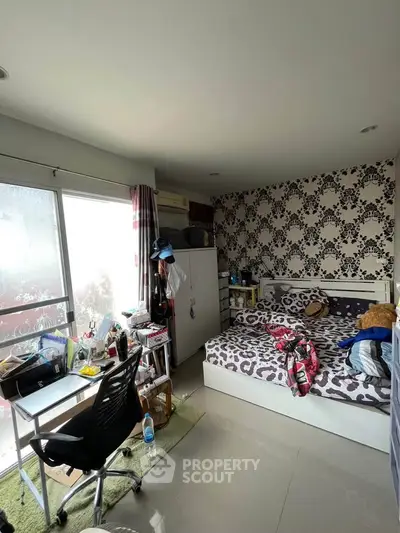 Cozy bedroom with stylish wallpaper and modern furniture, perfect for urban living.