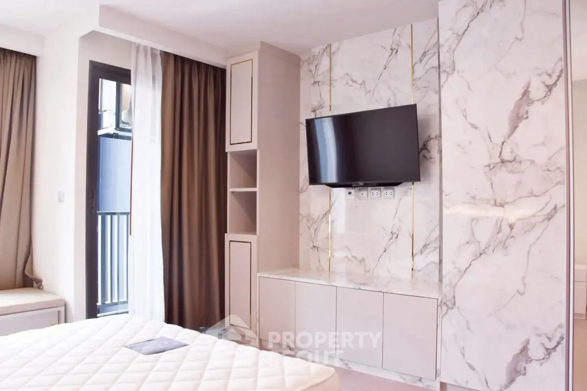 Modern bedroom with marble accent wall and mounted TV, featuring a balcony view.