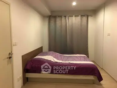 Cozy bedroom with modern decor and purple bedding, perfect for relaxation.