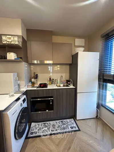 Modern kitchen with sleek appliances and washing machine, featuring a stylish open layout and ample natural light.