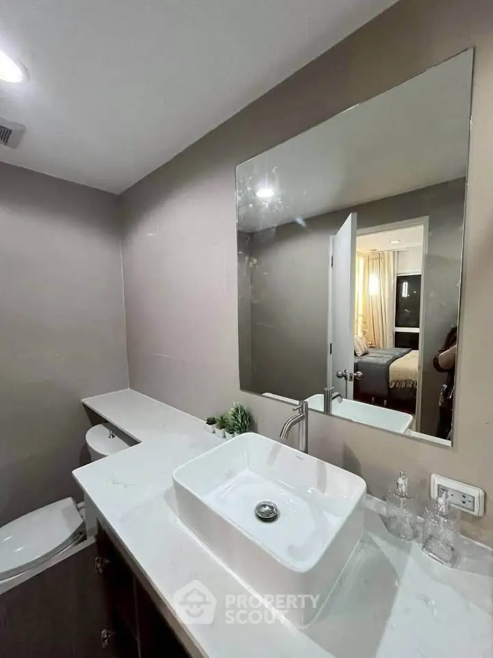 Modern bathroom with sleek sink and large mirror in stylish apartment.
