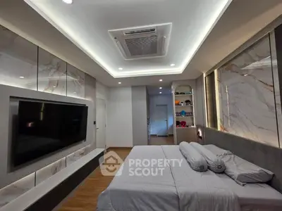 Luxurious modern bedroom with elegant lighting and large TV, perfect for relaxation and entertainment.