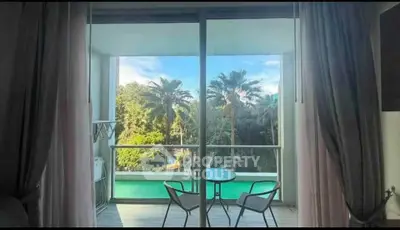 Stunning balcony view with lush greenery and pool, perfect for relaxation.
