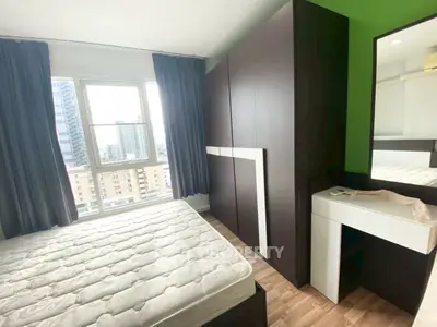 Modern bedroom with large window and city view, featuring sleek wardrobe and vanity desk.