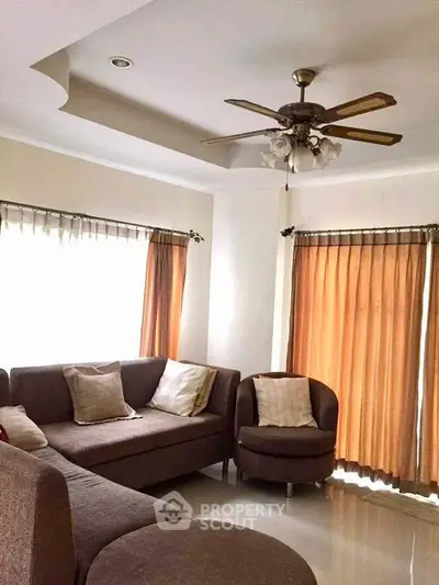 Cozy living room with brown sofas and ceiling fan, perfect for relaxation.