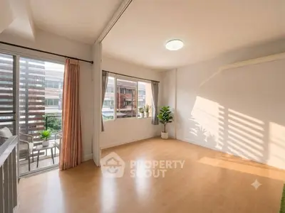 Spacious sunlit living room with balcony access and modern decor.