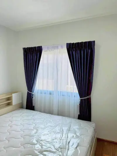 Bright bedroom with elegant dark curtains and a comfortable mattress, perfect for restful nights.