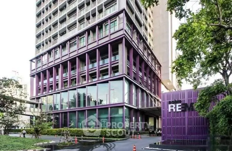 Modern high-rise building with unique purple facade and lush greenery in urban setting.