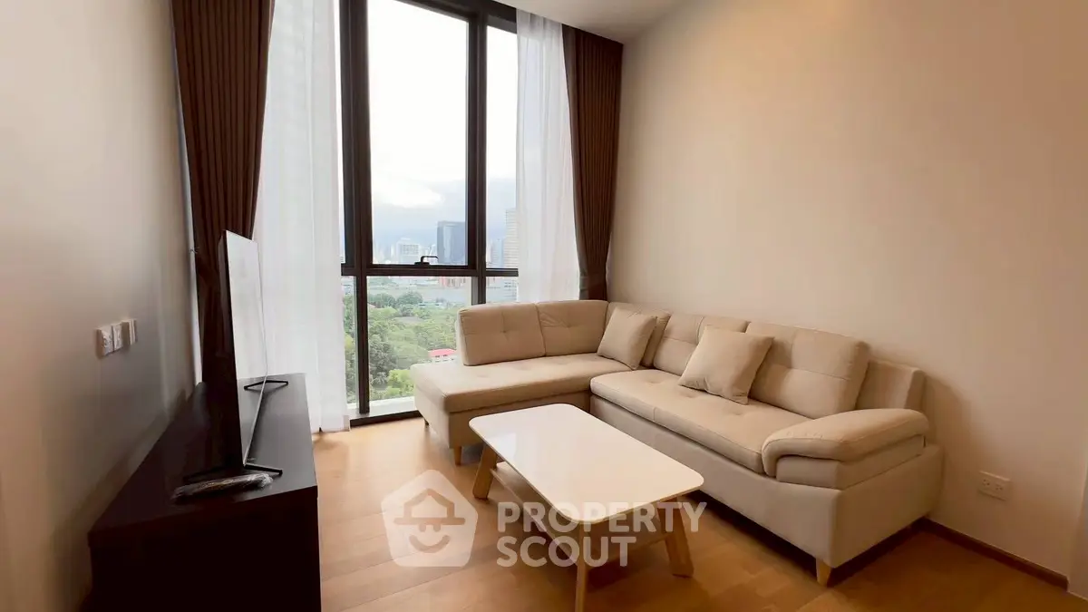Modern living room with large windows and city view, featuring a cozy sectional sofa and sleek TV stand.