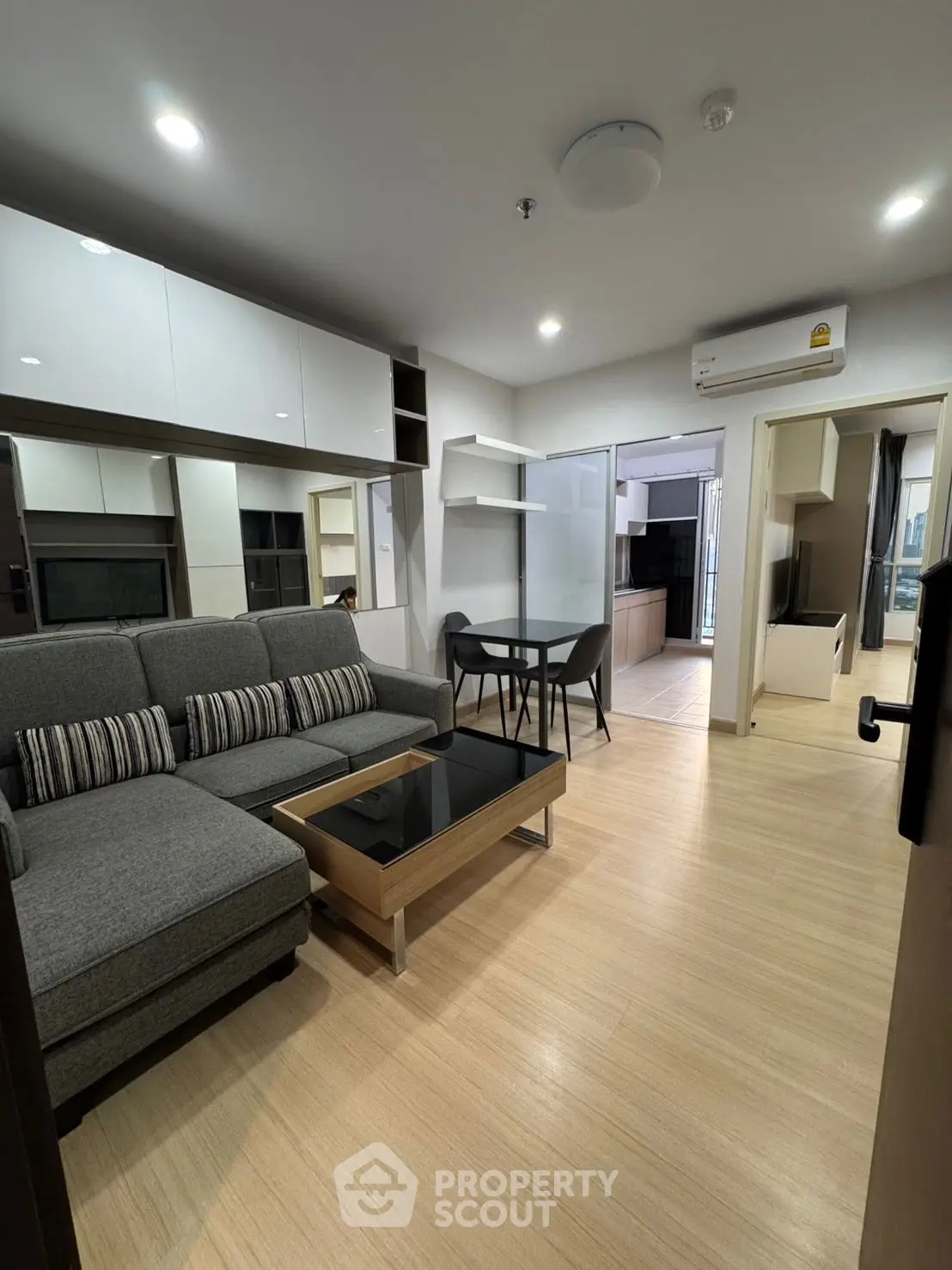 Modern living room with stylish furniture and open layout leading to kitchen area.