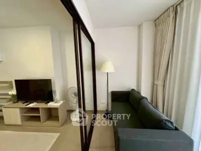 Modern living room with sleek black sofa, TV, and floor lamp, perfect for relaxation and entertainment.