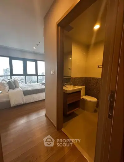 Modern apartment with cozy bedroom and compact bathroom, featuring large windows and city views.