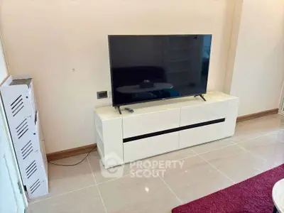Modern living room with sleek TV stand and flat-screen TV, featuring glossy tiled flooring and contemporary decor.
