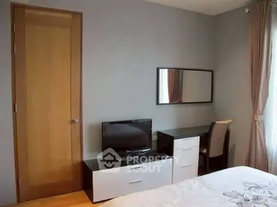 Cozy bedroom with TV, desk, and natural light from window.